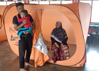 AMINAH Awang Hitam ditemani cucunya ketika ditempatkan di Pusat Pemindahan Sementara Sekolah Kebangsaan (SK) Teh di Jerantut, Pahang.