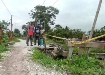 PENDUDUK  menunjukkan keadaan jambatan yang runtuh di Kampung Sungai Kurong, Chenderiang, Tapah. - UTUSAN/MEGAT LUTFI MEGAT RAHIM