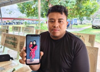 MOHAMMAD Syuqur Ahmad menunjukkan gambar isteri dan anaknya yang maut dalam nahas di Kilometer 212.3, Lebuhraya Pesisiran Pantai Barat (WCE), arah Selatan dekat Sitiawan hari ini. - UTUSAN/ASLIZA MUSA