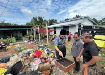 Timbalan Setiausaha (Operasi) MAINS, Datuk Nor Azmi Musa (kiri) melihat bongkah madu kelulut diusahakan Norazuan yang musnah akibat banjir di Felda Jelai 4, Tampin, Negeri Sembilan. - GAMBAR IHSAN MAINS