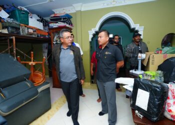 ADLY Zahari (kiri) semasa turun padang menyantuni rumah veteran ATM yang terkesan dengan banjir di Pasir Mas, Kelantan semalam.