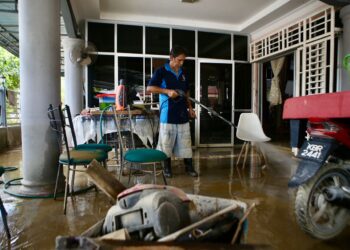 PENDUDUK membersihkan rumah masing-masing selepas banjir pulih di Taman Tabung Haji, Kepala Batas di Kubang Pasu. - UTUSAN/ SHAHIR NOORDIN