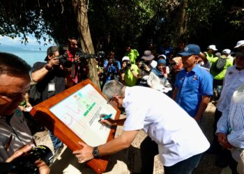 WAN Ahmad Dahlan Abdul Aziz, menandatangani plak perasmian Pintu Gerbang Denai Alam Aman, yang merupakan laluan denai mengelilingi Pulau Aman, Kampung Angkat Madani bagi Jabatan Perkhidmatan Awam (JPA), pada 8 Disember, lalu.