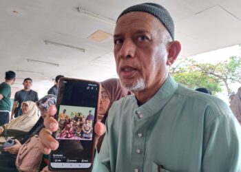 MAZUPI Abdul Rahman menunjukkan gambar keluarganya ketika ditemui di Jabatan Perubatan Forensik Hospital Melaka. - UTUSAN/MUHAMMAD SHAHIZAM TAZALI