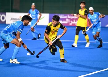 PEMAIN hoki remaja negara, Adam Ashraf Mohd Johari cuba melepasi pemain India dalam aksi separuh akhir Piala Remaja Asia di Stadium Hoki Oman, Muscat, semalam. -Ihsan Asian Hockey Federation