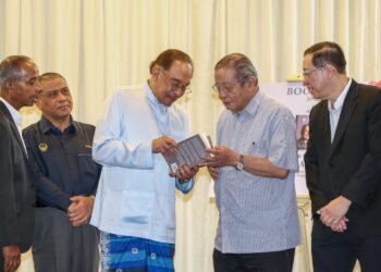 ANWAR Ibrahim melihat buku 'Malaysian First' pada pelancaran buku tersebut di Ipoh hari ini. - UTUSAN/MUHAMAD NAZREEN SYAH MUSTHAFA