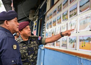 AYOB Khan Mydin Pitchay (kanan) melihat gambar kesan banjir ketika melawat Balai Polis Kuala Jengai, Dungun, Terengganu, hari ini. - UTUSAN/PUQTRA HAIRRY