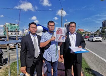 MUHAMMAD Syarifuddin Manan (tengah) menunjukkan laporan polis dan gambar kecederaan bayinya di Ibu Pejabat Polis  Kuala Terengganu, hari ini. - UTUSAN/ KAMALIZA KAMARUDDIN