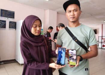 MOHAMAD Norzuhairi Noorisnien (kanan) bersama adiknya, Siti Norizyan Noorisnien menunjukkan gambar kenangan bersama arwah bapa ketika ditemui di Unit Perubatan Forensik Hospital Melaka. 
– UTUSAN/MUHAMMAD SHAHIZAM TAZALI