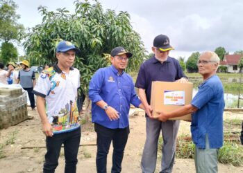 KHALID Samad (tiga kiri) menyampaikan bantuan pek makanan kepada seorang pesawah yang terjejas banjir di Kampung Jubakar Darat, Tumpat, Kelantan. - UTUSAN/ROHANA ISMAIL