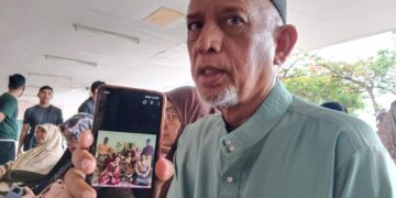 MAZUPI Abdul Rahman menunjukkan gambar keluarganya ketika ditemui di Jabatan Perubatan Forensik Hospital Melaka, baru-baru ini.- UTUSAN/MUHAMMAD SHAHIZAM TAZALI