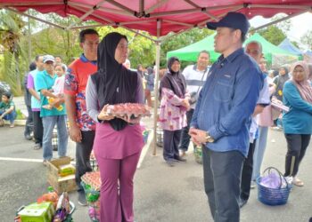 SAHARUDDIN Mohd Kia (kanan) beramah mesra dengan mangsa banjir yang membeli barangan keperluan di  Program Jualan Rahmah Madani (PJRM) Taman Desa Tanjung Damai di Terengganu, hari ini. - UTUSAN/KAMALIZA KAMARUDDIN