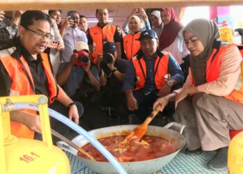 NORAINI Ahmad (kanan) membantu menyediakan masakan kepada mangsa banjir di Pusat Pemindahan Sementara (PPS) Sekolah Kebangsaan (SK) Kubang Kerian 2, Kota Bharu, Kelantan. - UTUSAN/ ROSLIZA MOHAMED