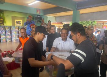 TENGKU Muhammad Ismail (kiri) berkenan menyantuni dan mengurniakan sumbangan kepada mangsa banjir di Sekolah Kebangsaan Kemasik, Kemaman, Terengganu, hari ini. - UTUSAN/NIK NUR IZZATUL HAZWANI NIK ADNAN