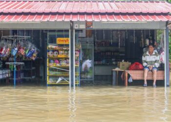 PEMILIK kedai runcit duduk di atas meja selepas kedainya di Kampung Baru Tok Kaya Kanan, Kemasik, Kemaman dilanda banjir gelombang kedua semalam. – UTUSAN/PUQTRA HAIRRY