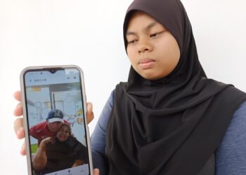 NUR Alyamyzara Muzaffa menunjukkan gambar kedua ibu bapanya ketika ditemui di Jabatan Perubatan Forensik Hospital Rembau hari ini.-UTUSAN/NOR AINNA HAMZAH.