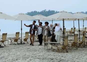 BEBERAPA pengunjung bergambar dengan berlatar belakang kemudahan payung pantai yang telah disediakan di Pantai Telok Kemang, Port Dickson.-UTUSAN/MOHD. SHAHJEHAN MAAMIN.