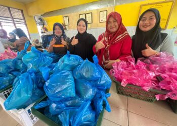 SHARIFAH Abdullah (dua dari kanan) bersama pekerjanya menyiapkan bungkusan makanan percuma di Sekolah Kebangsaan Cherang Ruku, Pasir Puteh, Kelantan, semalam. – UTUSAN/TOREK SULONG