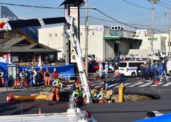 ANGGOTA bomba berusah mencari pemandu trak yang terjatuh dalam lubang benam di persimpangan jalan di bandar Yashio, wilayah Saitama.- AFP