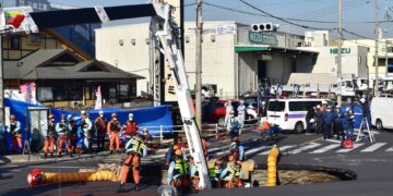 ANGGOTA bomba berusah mencari pemandu trak yang terjatuh dalam lubang benam di persimpangan jalan di bandar Yashio, wilayah Saitama.- AFP