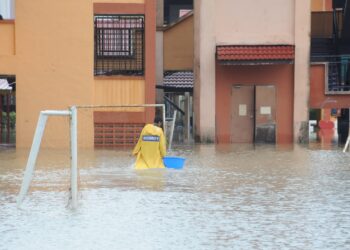 Seorang pengawal keselamatan meredah banjir yang melanda SK Kangkar Tebrau di Kampung Kangkar Tebrau, Johor Bahru disini. UTUSAN/RAJA JAAFAR ALI