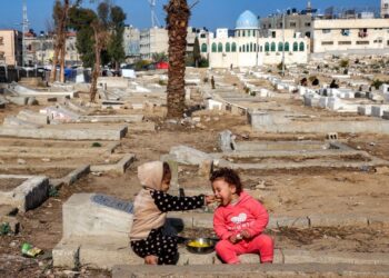 KANAK-KANAK menyuap makanan ketika mereka duduk di tanah perkuburan yang menjadi kawasan puluhan keluarga dipindahkan berlindung di Deir el-Balah di tengah Semenanjung Gaza.-AFP