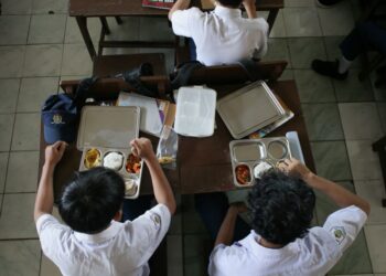 PELAJAR Sekolah Menengah Rendah PGRI 6 Bogor, Jawa Barat menikmati hidangan pada hari pertama program makanan percuma, semalam.- AFP