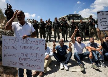 PENUNJUK perasaan duduk di hadapan pengawal sempadan Israel semasa protes di Beit Jala di Tebing Barat.-AFP