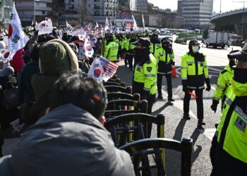 ANGGOTA polis mengawal penyokong Suk Yeol yang berkumpul berhampiran kediamannya di Seoul, Korea Selatan.-AFP