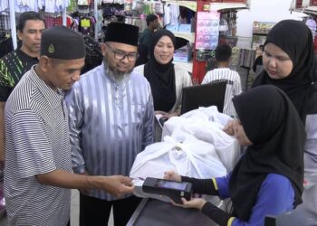 SEORANG penerima asnaf membuat pembayaran bantuan kelengkapan sekolah yang dikreditkan ke dalam kad pengenalan di Pasaraya Borong Sakan di Gambang, Kuantan, Pahang. - UTUSAN/ DIANA SURYA ABD WAHAB