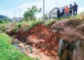 PENDUDUK menunjukkan keadaan runtuhan tebing berdekatan rumah yang semakin teruk di aman Puncak Bougainvillea di Kuala Kangsar semalam. – UTUSAN/FADZIL ZAINOL