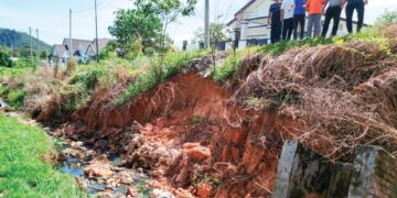 PENDUDUK menunjukkan keadaan runtuhan tebing berdekatan rumah yang semakin teruk di aman Puncak Bougainvillea di Kuala Kangsar semalam. – UTUSAN/FADZIL ZAINOL