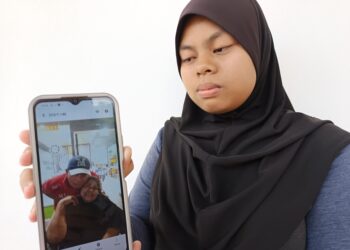 NUR Alyamyzara Muzaffa menunjukkan gambar kedua ibu bapanya ketika ditemui di Jabatan Perubatan Forensik Hospital Rembau hari ini. - UTUSAN/NOR AINNA HAMZAH