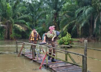 SEORANG anggota bomba mendukung seorang wanita warga usia emas untuk dibawa  ke PPS Komplek Muafakat Sungai Pinggan di Benut, Pontian, Johor.