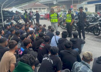 SAZALEE Adam (berdiri, tiga dari kanan) memberi nasihat kepada para penunggang motosikal yang ditahan atas pelbagai kesalahan termasuk terlibat dengan perlumbaan haram di JSAHMS atau Jambatan Kedua Pulau Pinang, malam tadi.