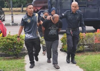 MOHD Nasir Othman (depan, tengah) dan isteri (belakang) diiringi beberapa anggota polis ketika dibawa ke Mahkamah Sesyen Balik Pulau, Pulau Pinang hari ini.-UTUSAN/IQBAL HAMDAN