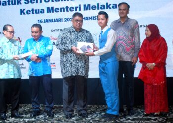 AB. RAUF Yusoh menyampaikan peranti tablet kepada seorang pelajar pada Majlis Penyerahan Kit Peranti dan Sijil Kolaboratif Program Anak Kita Peringkat Negeri di Ayer Keroh, Melaka. - UTUSAN/AMRAN MULUP