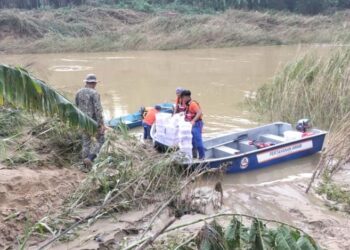 ANGGOTA Angkatan Pertahanan Awam (APM) membantu menghantar barang keperluan kepada penduduk terperangkap banjir di Pitas, Sabah.-GAMBAR/IHSAN APM