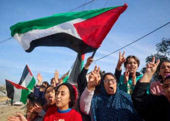 Rakyat Palestin mengibarkan bendera negara mereka ketika pulang ke Rafah di Selatan Semenanjung Gaza, ekoran pelaksanaan gencata senjata antara Israel dan Hamas semalam. - AFP