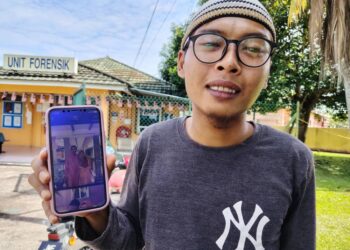 Mohamad Farhan Jamian menunjukkan gambar abangnya, Allahyarham Mohamad Osman yang terkorban dalam kemalangan jalan raya di Kampung Parit Jawa, Pontian, Johor semalam.