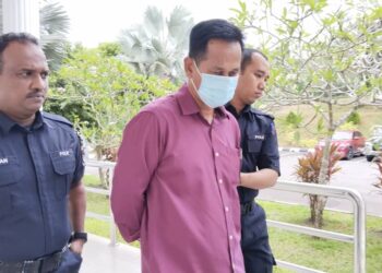 TERTUDUH diiringi anggota polis ketika dihadapkan ke Mahkamah Majistret, Alor Gajah, Melaka. - UTUSAN/MUHAMMAD SHAHIZAM TAZALI