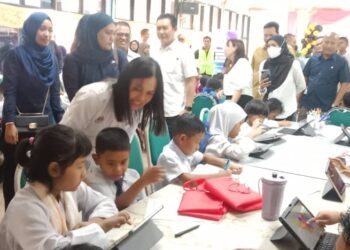 TEO Nie Ching (tunduk) menyantuni murid Orang Asli sedang mengakses maklumat menggunakan tablet di Sekolah Kebangsaan Bukit Rok di Bera, Pahang. - FOTO/HARIS FADILAH AHMAD