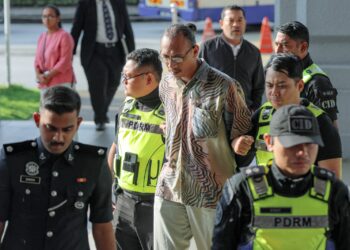 IZZUDIN Md. Salim (tengah) diiringi anggota polis tiba bagi didakwa atas pertuduhan membuat ugutan kepada pelawak, Harith Iskander dan keluarga di Mahkamah Majistret Kuala Lumpur, hari ini.-UTUSAN/FARIZ RUSADIO.