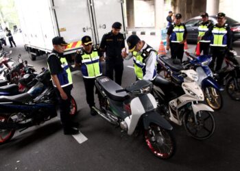 MOHAMMAD Yusoff Abustan (tengah) memeriksa motosikal yang disita dalam operasi di Jalan Tambun, Ipoh hari ini. - UTUSAN