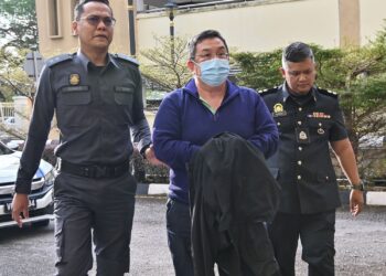 EWE Sern Yeun (berpelitup muka) didakwa atas penemuan produk yang diragui status halal, tiba di Mahkamah Sesyen Petaling Jaya, semalam. – UTUSAN/SYAKIR RADIN