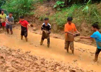 PENDUDUK Orang Asli mengangkat batu sungai untuk membaiki jalan di Pos Pasik, Gua Musang, Kelantan, semalam.- IHSAN PENDUDUK