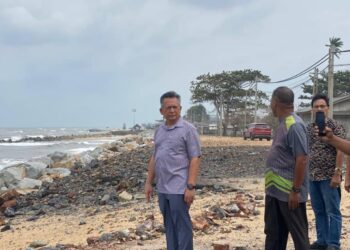 AHMAD Razif (kiri) meninjau keadaan terkini hakisan yang berlaku di Pantai Mengabang Telipot, Kuala Nerus, Terengganu. – UTUSAN/KAMALIZA KAMARUDDIN