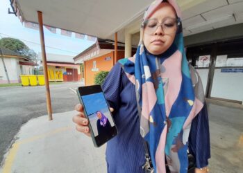 SITI Nurul Fatihah Mahmud menunjukkan gambar Allahyarham Siti Nabila yang maut dalam kemalangan di Kilometer 52 Jalan Johor 
Bahru-Mersing, petang kelmarin.