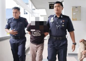 TERTUDUH diiringi anggota polis ketika dihadapkan ke Mahkamah Sesyen Ayer Keroh, Melaka.