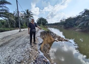 YAHYA Ahmad menunjukkan jalan yang runtuh akibat hakisan sungai di Kampung Baru Seberang Binjai, Setiu, Terengganu. – UTUSAN / WAN ZURATIKAH IFFAH WAN ZULKIFLI